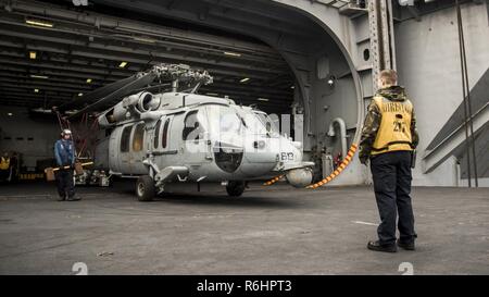 WESTERN PACIFIC (May 16, 2017) Airman Robert Young, of Tabares, Florida, left, and Aviation Boatswain’s Mate (Handling) 3rd Class Sarah-Katie Prielipp, of Ann Arbor, Michigan, move an MH-60S Sea Hawk from the Helicopter Sea Combat Squadron (HSC) 4 “Black Knights” onto an aircraft elevator aboard the Nimitz-class aircraft carrier USS Carl Vinson (CVN 70) hangar bay. The U.S. Navy has patrolled the Indo-Asia-Pacific routinely for more than 70 years promoting regional peace and security. Stock Photo