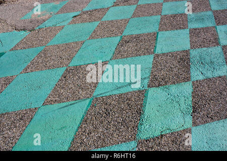 Pattern of green squares on asphalt. Looks like racing finish line. Rough tar, dirt and green paint. Stock Photo