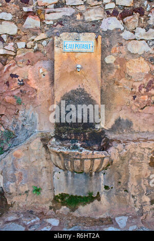 Old drinking water fountain in southern France with a blue sign saying 'drinking water' in French. Stock Photo