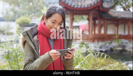 Woman use of smart phone in the chinese pavilion garden Stock Photo