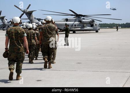 A group of Marines walk towards a CH-53E Super Stallion during a field trip at Marine Corps Air Station New River, N.C., May 16, 2017. Marines assigned to the Marine Corps Air Station Cherry Point Squadron Intelligence Training Certification Course had the opportunity to visit various units stationed at MCB Camp Lejeune, N.C. and MCAS New River, N.C., in order to provide them a better understanding about capabilities and limitations of aircraft, weapons systems and vehicles their units may utilize. Stock Photo