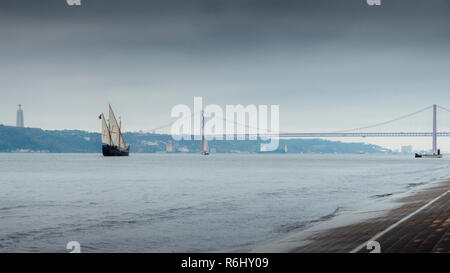 Traditional Portuguese caraval on River Tagus, Lisbon, Portugal with 25 April Bridge in background. Stock Photo