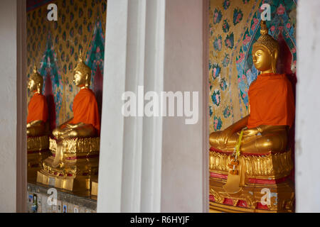 Three of the several golden Buddha statues lined up in a diminishing perspective under the cover of one of the Ordination Hall in Bangkok, Thailand. Stock Photo