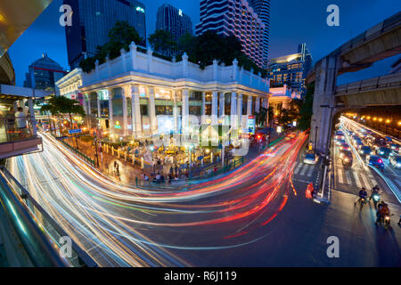 Creative high angle night shot of Ratchaprasong Intersection and Erawan Shrine in Bangkok, Thailand, with colourful light trail from cars driving past Stock Photo