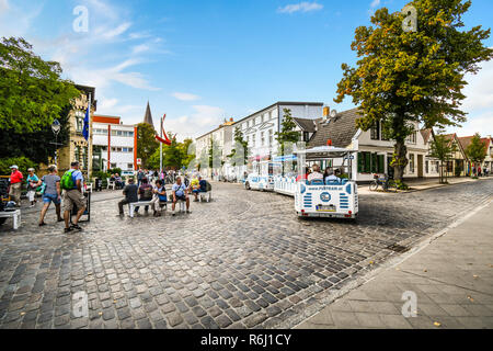 Tourists ride a tour tram through the streets of the coastal resort city of Warnemunde, Rostock, Germany. Stock Photo