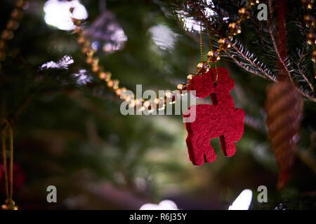 A red felt reindeer and gold beads hang on a Christmas tree Stock Photo