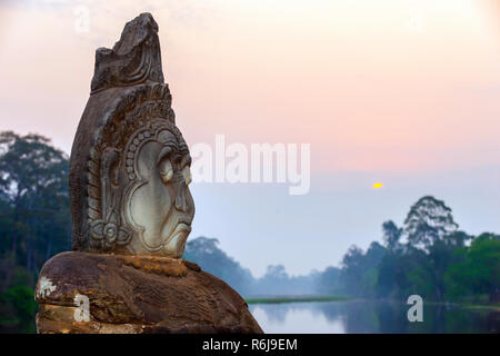 Sunrise over lake and in between row of gods on path to  Angkor Thom, South Gate,  Siem Reap, Cambodia, Southeast Asia Stock Photo