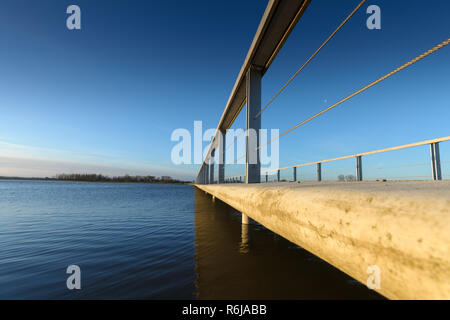 Details of a concrete walkway along the waterfront against a river dike overlooking the water and the delta. Empty bridge / walkway background with co Stock Photo