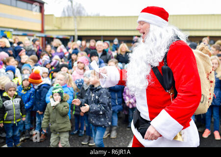 Lustadt, Germany. 06th Dec, 2018. A motorcyclist disguised as Santa Claus sings a Christmas song on St. Nicholas Day in the schoolyard in front of primary school pupils under the motto 'Harley Davidson riding Santas'. During the day, they visit several children's and senior citizens' homes in the region and call for support for a home for children with cancer. Credit: Uwe Anspach/dpa/Alamy Live News Stock Photo
