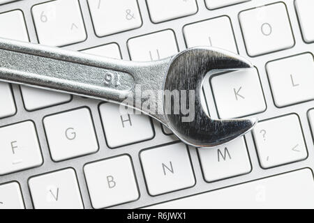 Wrench and computer keyboard. Metallic spanner on keyboard. Stock Photo