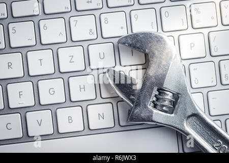 Wrench and computer keyboard. Metallic spanner on keyboard. Stock Photo