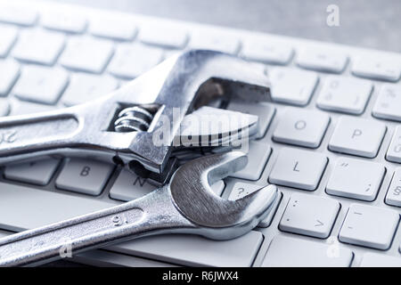 Wrench and computer keyboard. Metallic spanner on keyboard. Stock Photo