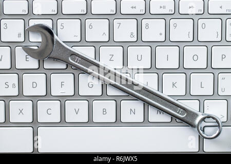 Wrench and computer keyboard. Metallic spanner on keyboard. Stock Photo