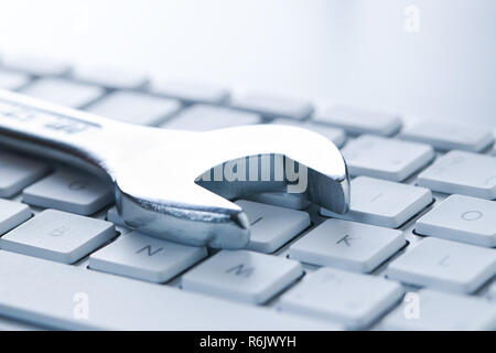 Wrench and computer keyboard. Metallic spanner on keyboard. Stock Photo