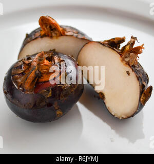 Fresh water chestnuts (Eleocharis dulcis) on a white plate, including a cross-section. Stock Photo