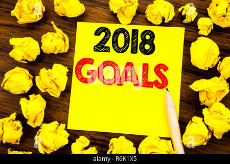 Writing text showing 2018 Goals. Business concept for New Yer resolutions Written on sticky note paper, wooden background with folded yellow paper meaning thinking Stock Photo