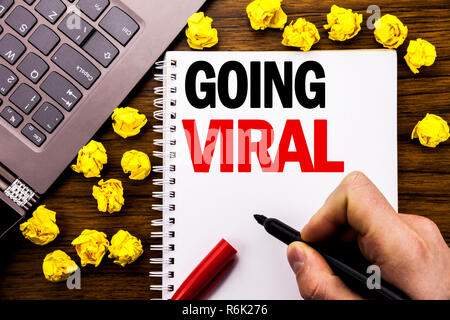 Conceptual hand writing text caption Going Viral. Business concept for Social Viral Business Written on tablet laptop, wooden background with businessman hand, finger holding PC. Stock Photo