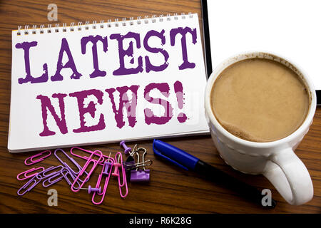 Hand writing text caption inspiration showing Latest News. Business concept for Fresh Current New Story written on note paper on the wooden background with coffee and pen Stock Photo