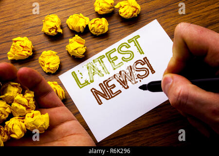 Word, writing Latest News. Concept for Fresh Current New Story written on notebook note paper on the wooden background with folded paper meaning thinking for idea. Man hand and marker. Stock Photo