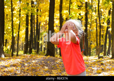 Girl playing hide and seek in autumn park Stock Photo
