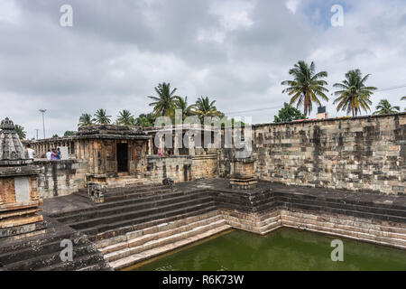 Belur, Karnataka, India - November 2, 2013: Chennakeshava Temple. Brown stone dilapidated shrine in corner of the grounds adjacent to green water tank Stock Photo