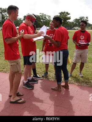 Volunteers review the line-up for the wheelchair racing events during the Special Olympics Mississippi 2017 Summer Games May 20, 2017, on Keesler Air Force Base, Miss. Founded in 1968, Special Olympics hosts sporting events around the world for people of all ages with special needs to include more than 700 athletes from Mississippi. Stock Photo