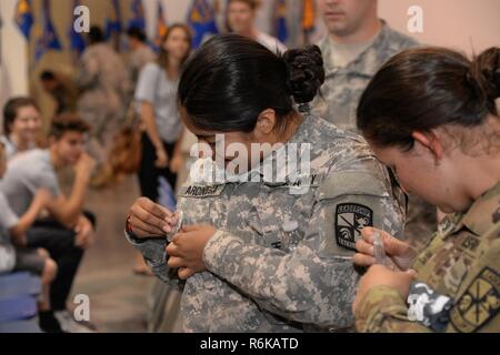 Madelyn Arciniega, a Reserve Officer Training Corps cadet at the University of California Davis, pins a button featuring Spc. Adam Kinser to her uniform prior to the 7th Annual Gold Star Families Ruck March May 20, 2017 at Travis Air Force Base, Calif. The event is held every year by the Travis First Sergeant's Council to support Gold Star Families. Kinser was killed while on patrol in Afghanistan in January 2004. Stock Photo