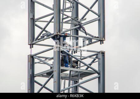 Rotterdam, The Netherlands, August 27, 2018: Two construction workers working on the montage of two vertical trusses of a tower crane Stock Photo