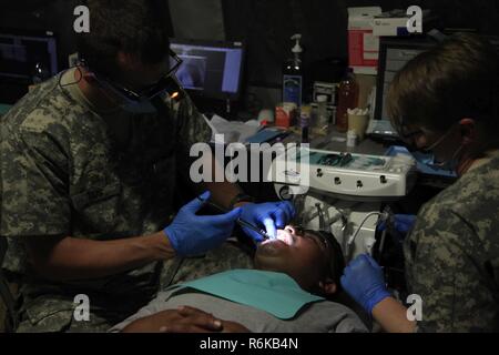 U.S. Army Maj. Aaron Taff, a dentist with the Wyoming National Guard Medical Detachment, administers a numbing anesthetic to a patient at a medical readiness event during Beyond the Horizon 2017, in San Ignacio, Belize, May 14, 2017. BTH 2017 is a U.S. Southern Command-sponsored, Army South-led exercise designed to provide humanitarian and engineering services to communities in need, demonstrating U.S. support for Belize. Stock Photo