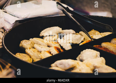 Fried dumplings, filled with meat cooking at the pan on the street. Traditional Christmas Eve pierogi. Street national food. Stock Photo