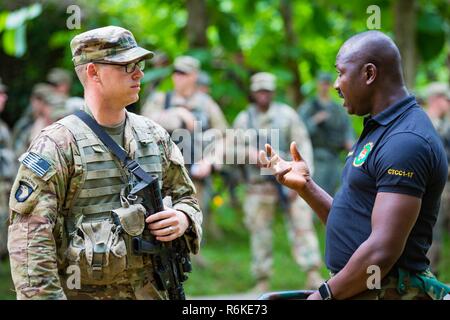 Ghana Armed Forces Maj. Jacob Codjoe, course commander of the Jungle Warfare School, discuss training with U.S. Army Staff Sgt. Ty Kurtz assigned to the 1st Battalion, 506th Infantry Regiment, 1st Brigade Combat Team, 101st Airborne (Air Assault) Division during United Accord 2017 at the Jungle Warfare School in Achiase military base, Akim Oda, Ghana, May 20, 2017. The Jungle Warfare School is a series of situational training exercises designed to train participants in counter-insurgency and internal security operations. Stock Photo