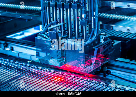 Electronic circuit under surface-mounting machine. Shot in blue toning filter. Surface-mount technology as a producing of electronic circuits. Components placed onto the surface of printed elements. Stock Photo