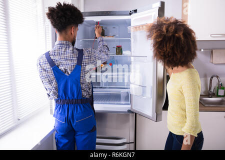 Repairman Checking Refrigerator With Digital Multimeter Stock Photo