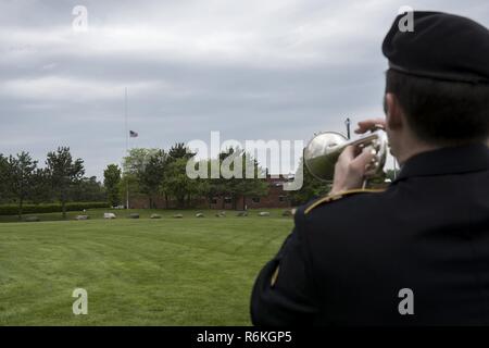 U.S. Army Staff Sgt. Jay Ginns, 40th Army Band, 86th Troop Command, Garrison Support Command, Vermont National Guard, performs taps as the American flag is lowered to half-staff, during a Memorial Day ceremony at Camp Johnson, Colchester, Vt., May 25, 2017. This ceremony gave Soldiers, Airmen and family members an opportunity to honor those who have paid the ultimate sacrifice in service to their country. Stock Photo