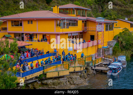 CUICOCHA, ECUADOR, NOVEMBER 06, 2018: Above view of yellow information building with some tourists boarding a boat to have a tour in the Cuicocha lake Stock Photo