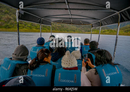 CUICOCHA, ECUADOR, NOVEMBER 06, 2018: Tourists inside of a tour boats along at Laguna Cuicocha Ecuador, weraring a blue safe vest Stock Photo