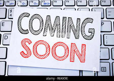 Handwritten text caption showing Coming Soon. Business concept writing for Under Construction written on sticky note paper on the white keyboard background. Stock Photo