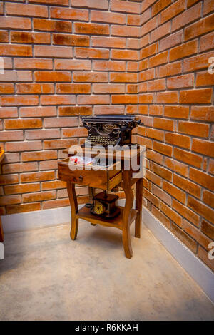 OTAVALO, ECUADOR, NOVEMBER 06, 2018: Outdoor view of an old typewriter and old telephone in a wooden pedestal table located in Cotacachi, Ecuador. Stock Photo