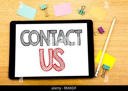 Writing text showing Contact Us. Business concept for Customer Support Written on tablet laptop, wooden background with sticky note and pen Stock Photo