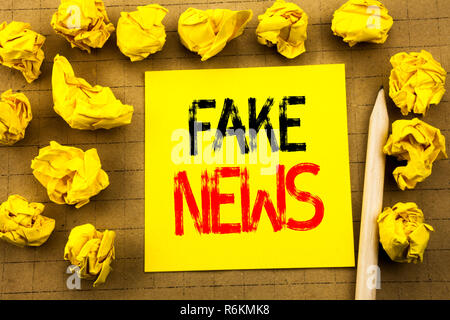 Fake News. Business concept for Hoax Journalism written on sticky note paper on the vintage background. Folded yellow papers on the background Stock Photo