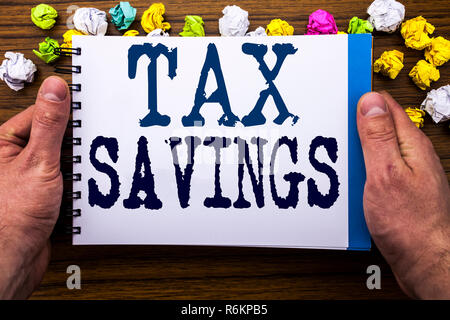 Writing text showing Tex Savings . Business concept for Tax Savings Extra Money Refund written on notepad notebook book on the wooden wood background with man businessman hand and finger. Stock Photo