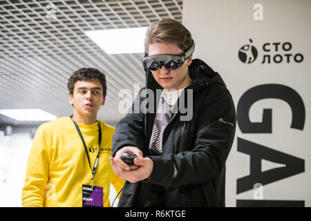 MOSCOW, RUSSIA - OCTOBER 27 2018. Young man using virtual reality headset and drawing with special joystick at technology exhibition. Augmented reality and entertainment concept Stock Photo