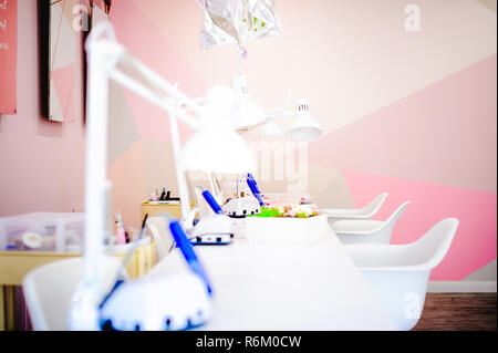 Workplace in a bright manicure salon. Working table of the master of nail service, chairs and lamps Stock Photo