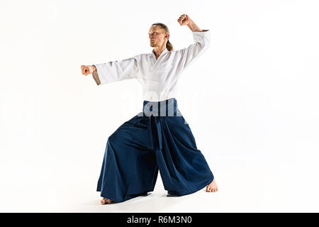 Aikido master practices defense posture. Healthy lifestyle and sports concept. Man with beard in white kimono on white background. Stock Photo