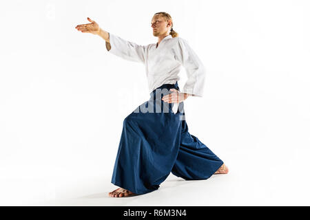 Aikido master practices defense posture. Healthy lifestyle and sports concept. Man with beard in white kimono on white background. Stock Photo