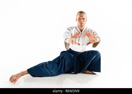 Aikido master practices defense posture. Healthy lifestyle and sports concept. Man with beard in white kimono on white background. Stock Photo