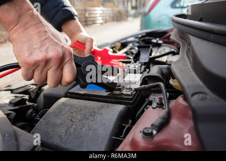 Person Using Jumper Cables To Charge Car's Dead Battery Stock Photo