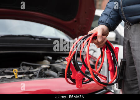 Close-up Of A Person Holding Jumper Cables Stock Photo