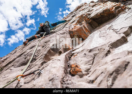 The last movements to reach the summit by a male climber. Rock climbing inside Andes mountains and valleys at Cajon del Maipo, an amazing place Stock Photo