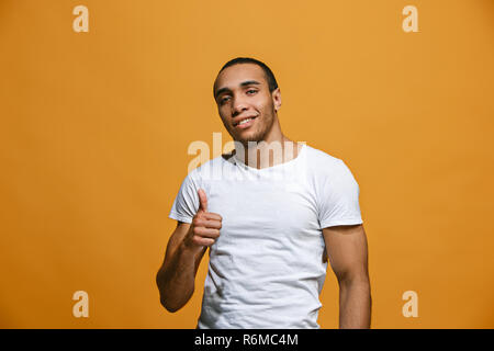 The happy businessman standing and smiling against orange background. Stock Photo